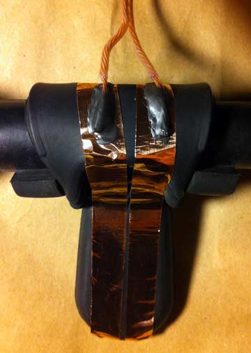 Close up of the electrified bit gag shoing the separate strips of copper tape making up the two electrodes and the conductive glue holding the wires connecting the mouth electrodes to the shock collar, which acts as the power supply.