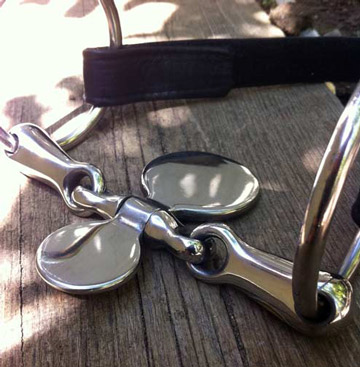 A jointed metal snaffle with spoon mouthpiece with velcro attaching strap
